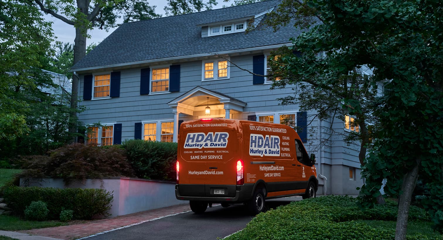 A Hurley and David service van parked in a residential driveway at night, arriving to provide emergency electrical services.