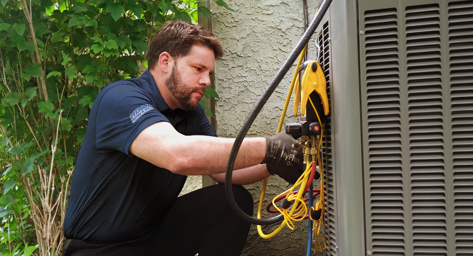 A professional Hurley and David HVAC technician inspecting an outdoor central air conditioning unit to provide residential AC repair and diagnostic services.